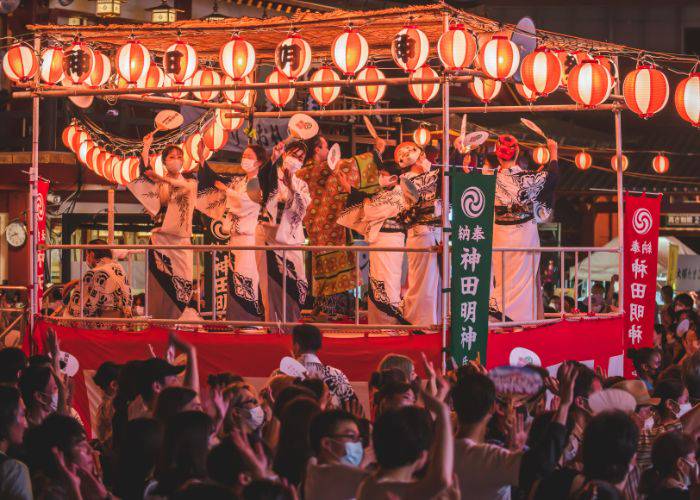 A vibrant Bon Odori parade, featuring a stage of dancers in cotton kimono.